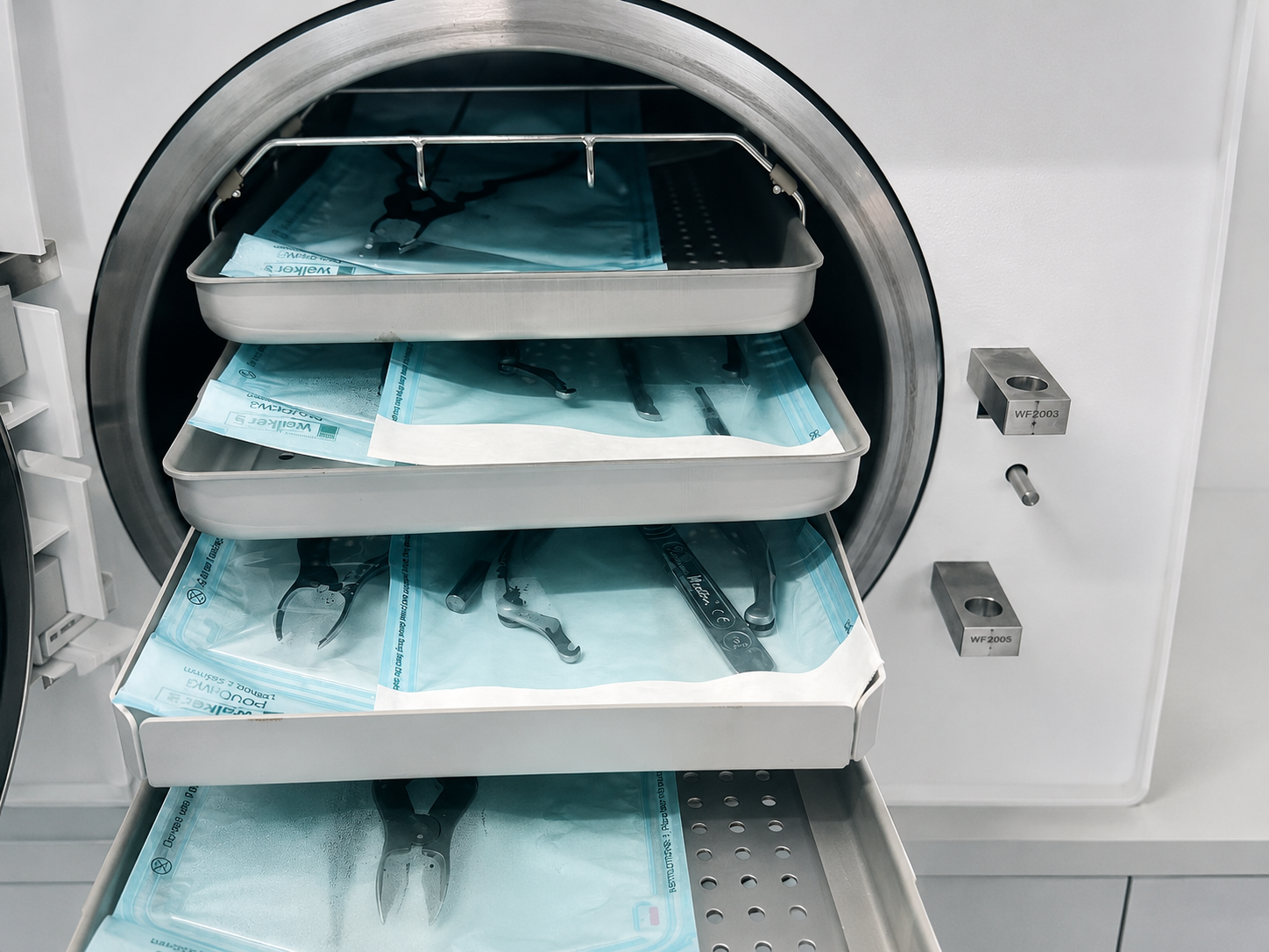 Sterilised instruments in sealed pouches arranged on autoclave trays
